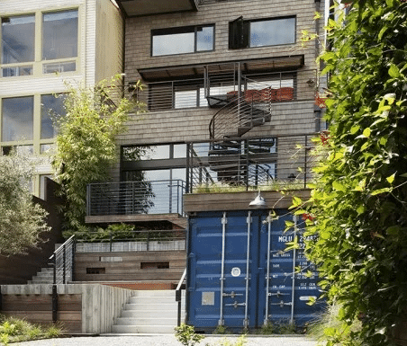 Modern house with a blue shipping container and an exterior spiral staircase.