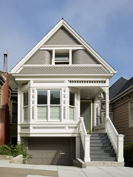A light gray Victorian house with ornate trim, bay windows, and a front porch.